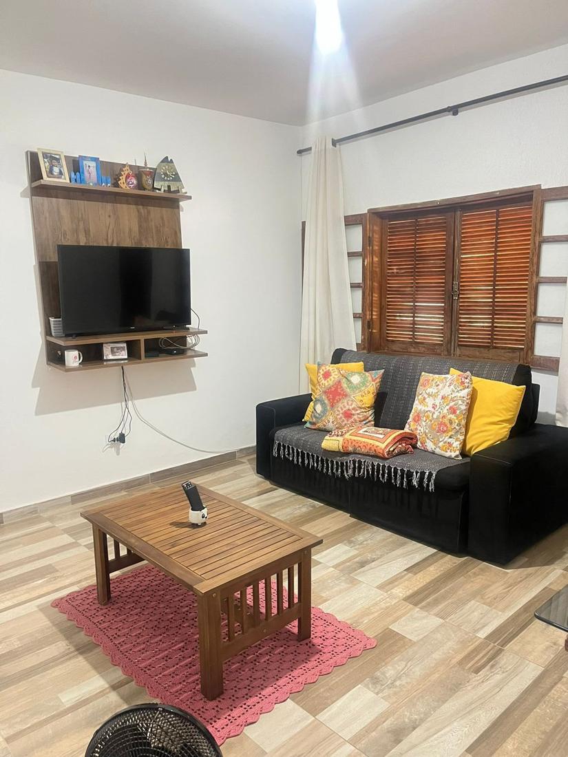 Sala de TV com painel, sofá e janela de madeira